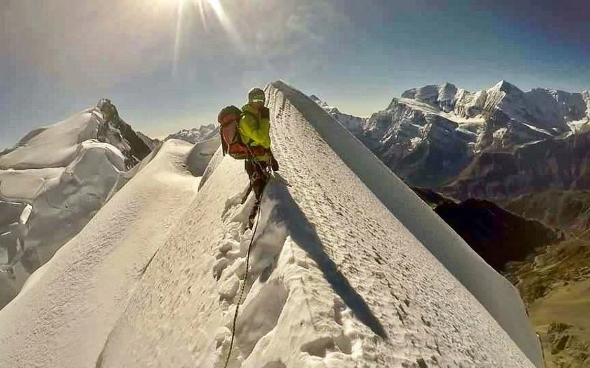 Climber ascending a steep snow ridge on Chulu West