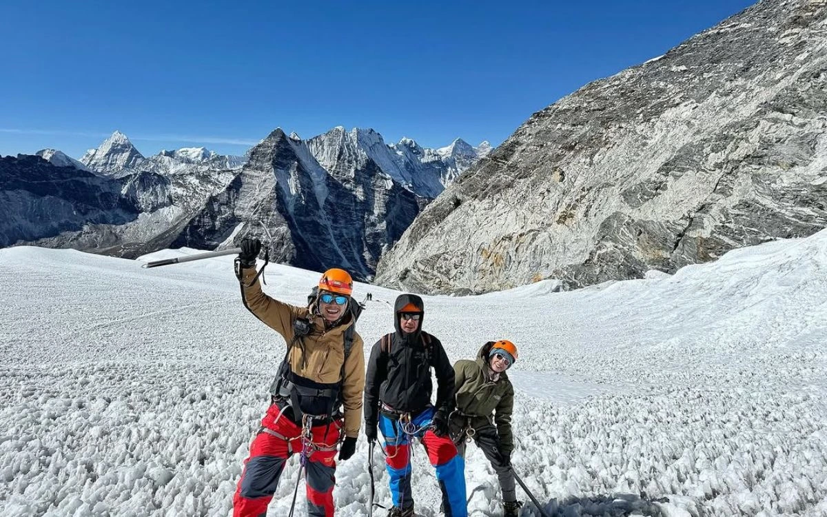 Three climbers posing on Island Peak glacier with Himalayan peaks behind