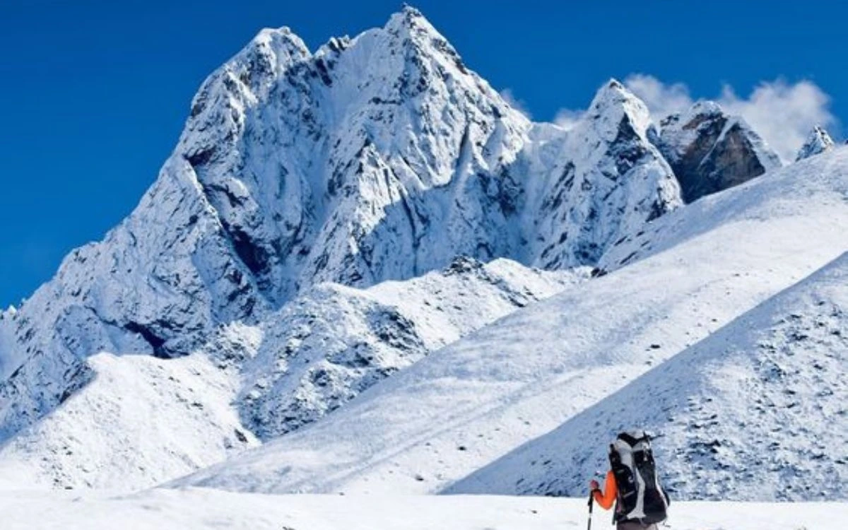 Solo trekker approaching the jagged snowy face of Pisang Peak