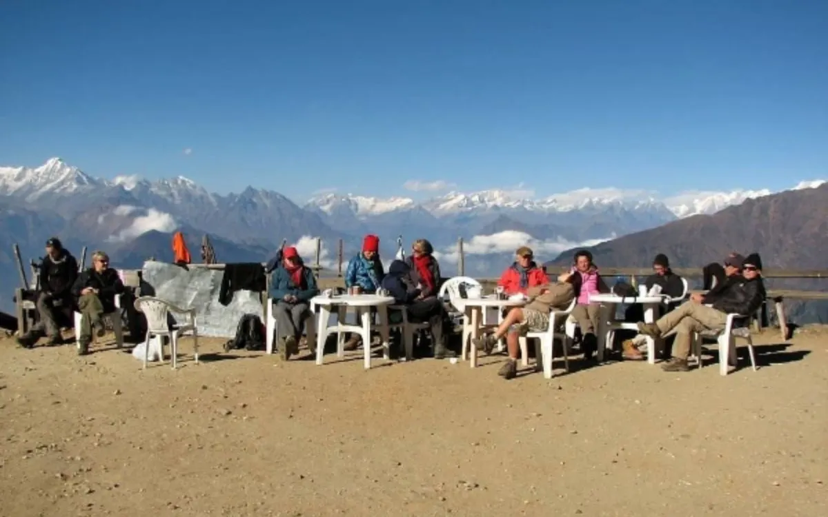 Trekking group resting at mountain viewpoint with Himalayan range backdrop
