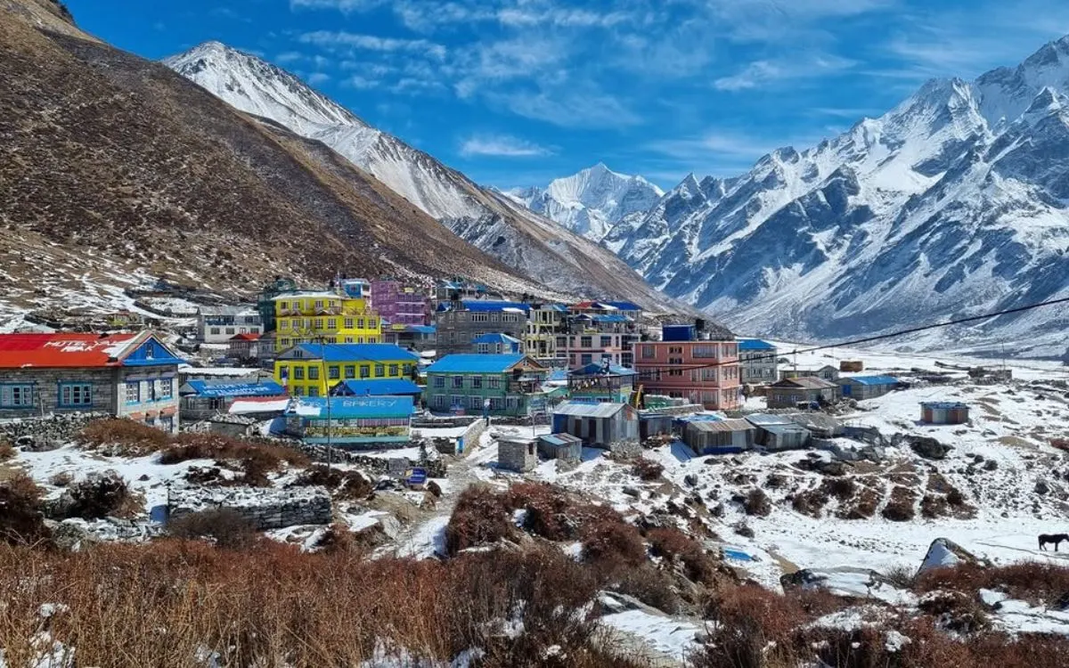 Colorful mountain village with snow-capped Himalayan peaks in background