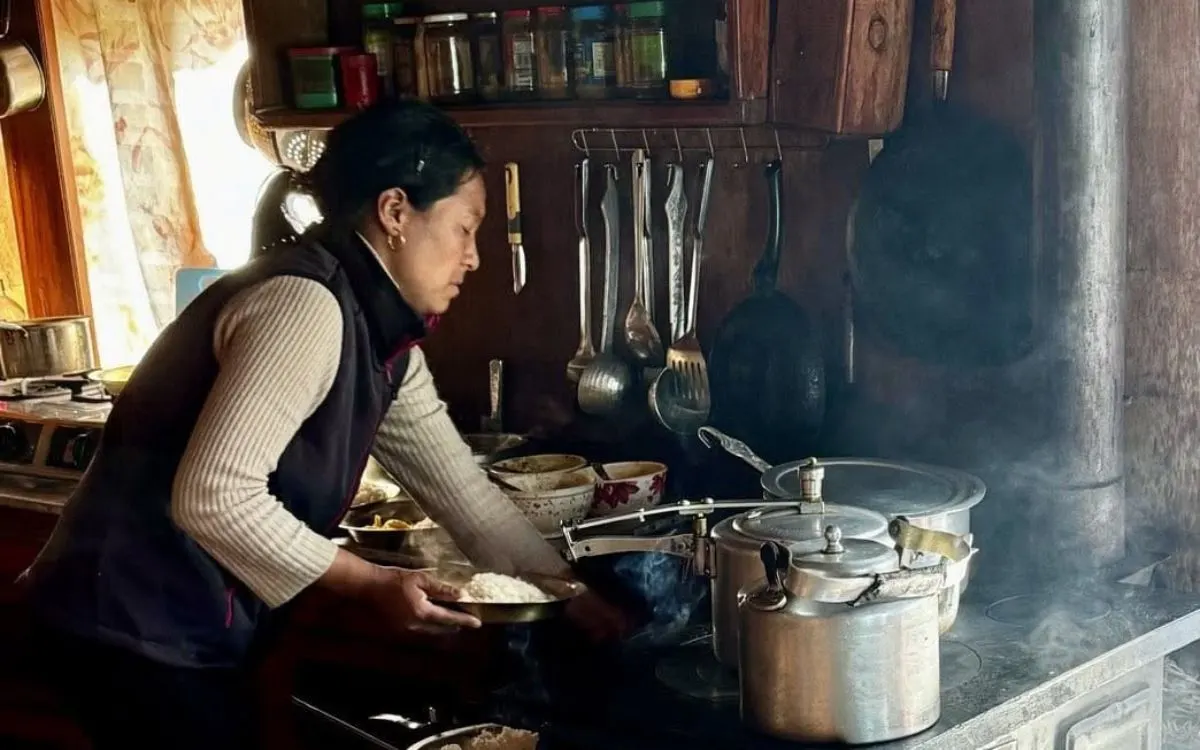 Local woman cooking on wood-fired stove in mountain lodge kitchen