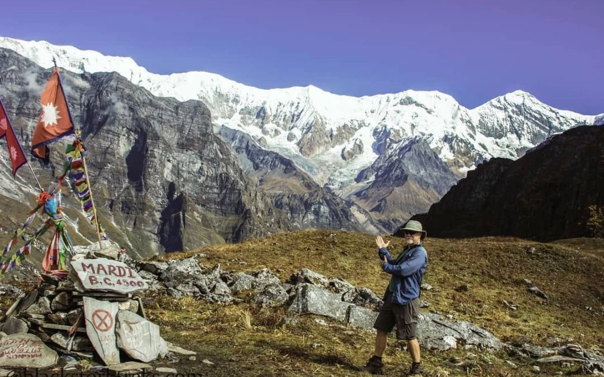 Trekker at Mardi Base Camp sign with Annapurna range, Nepal