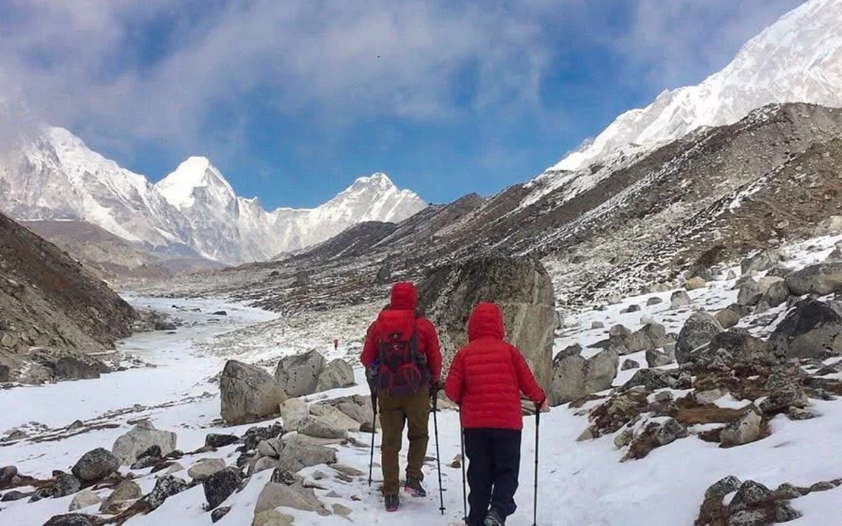Two trekkers in red jackets on a snowy Everest region trail