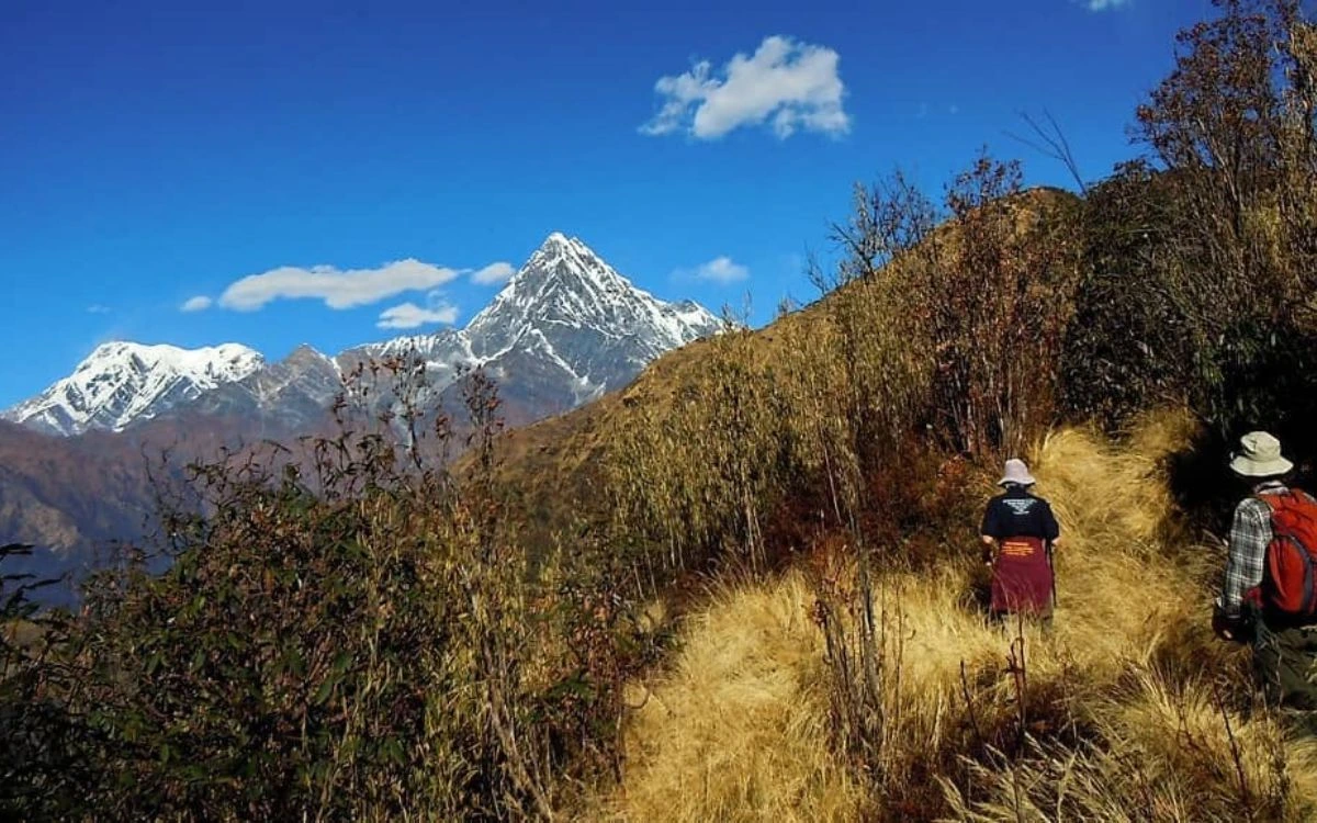 Hikers on a grassy ridge trail with Machhapuchhre peak in the distance