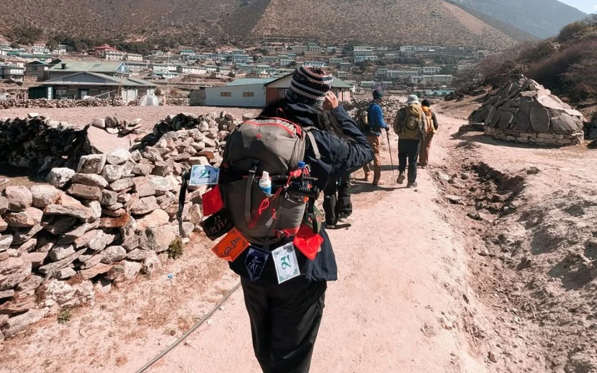 Trekker with backpack walking through mountain village with traditional buildings