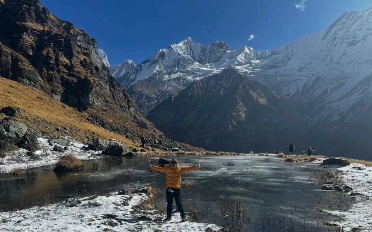 Trekker at a frozen lake near Annapurna Base Camp in cold weather”