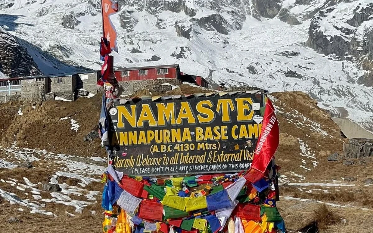 Namaste Annapurna Base Camp welcome sign at 4130m decorated with colorful prayer flags