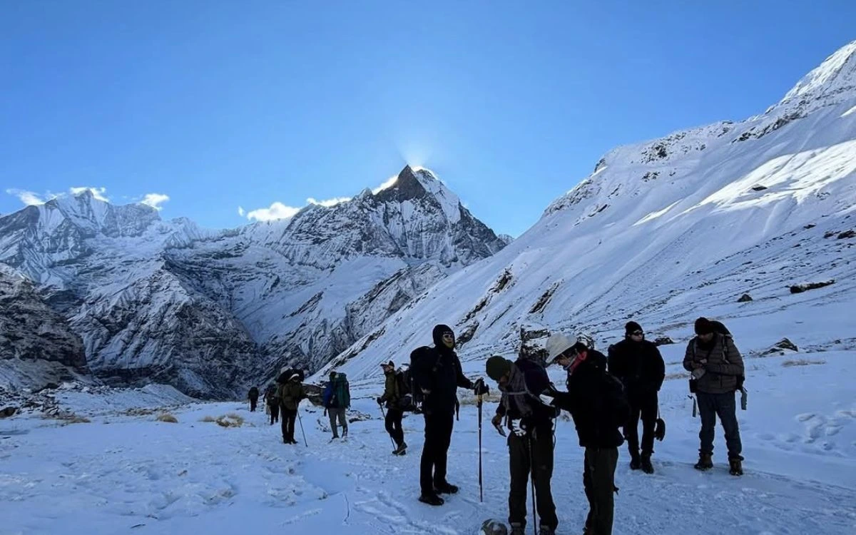 Group of trekkers on a snow-covered trail with Machhapuchhre peak towering behind in October