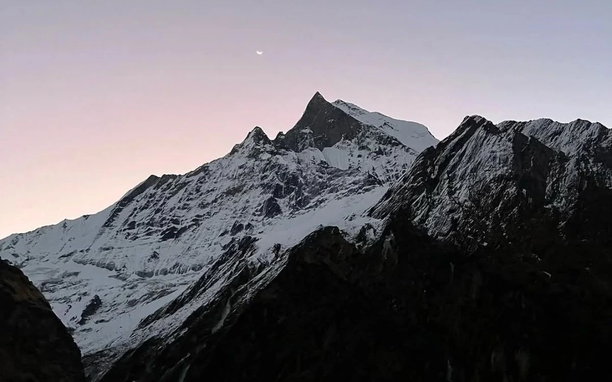 Machhapuchhre peak at dusk with a crescent moon and soft pink twilight sky