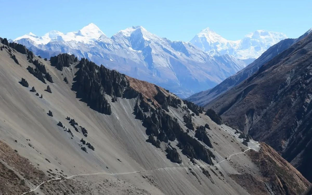 Jagged eroded ridgeline on the Annapurna Circuit with snow-capped Himalayan peaks in the distance