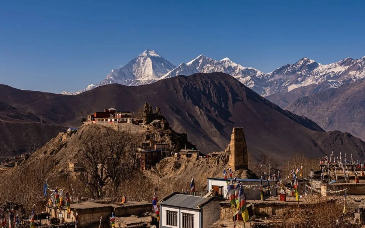 Tibetan Buddhist monastery on hilltop with snow-capped Himalayan peaks