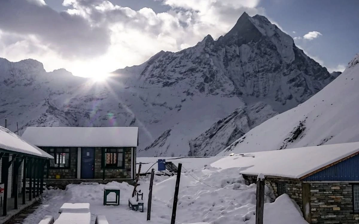 Snow-covered mountain lodges at Annapurna Base Camp with peak behind