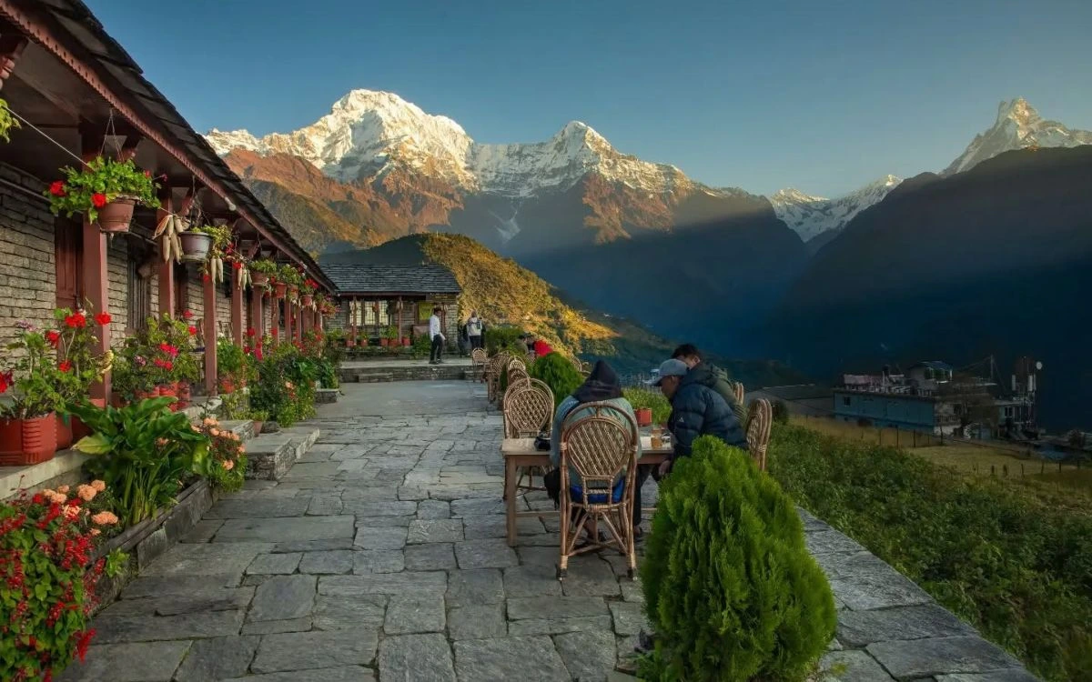 Trekkers resting at a flower-lined lodge terrace on the way to Annapurna Base Camp