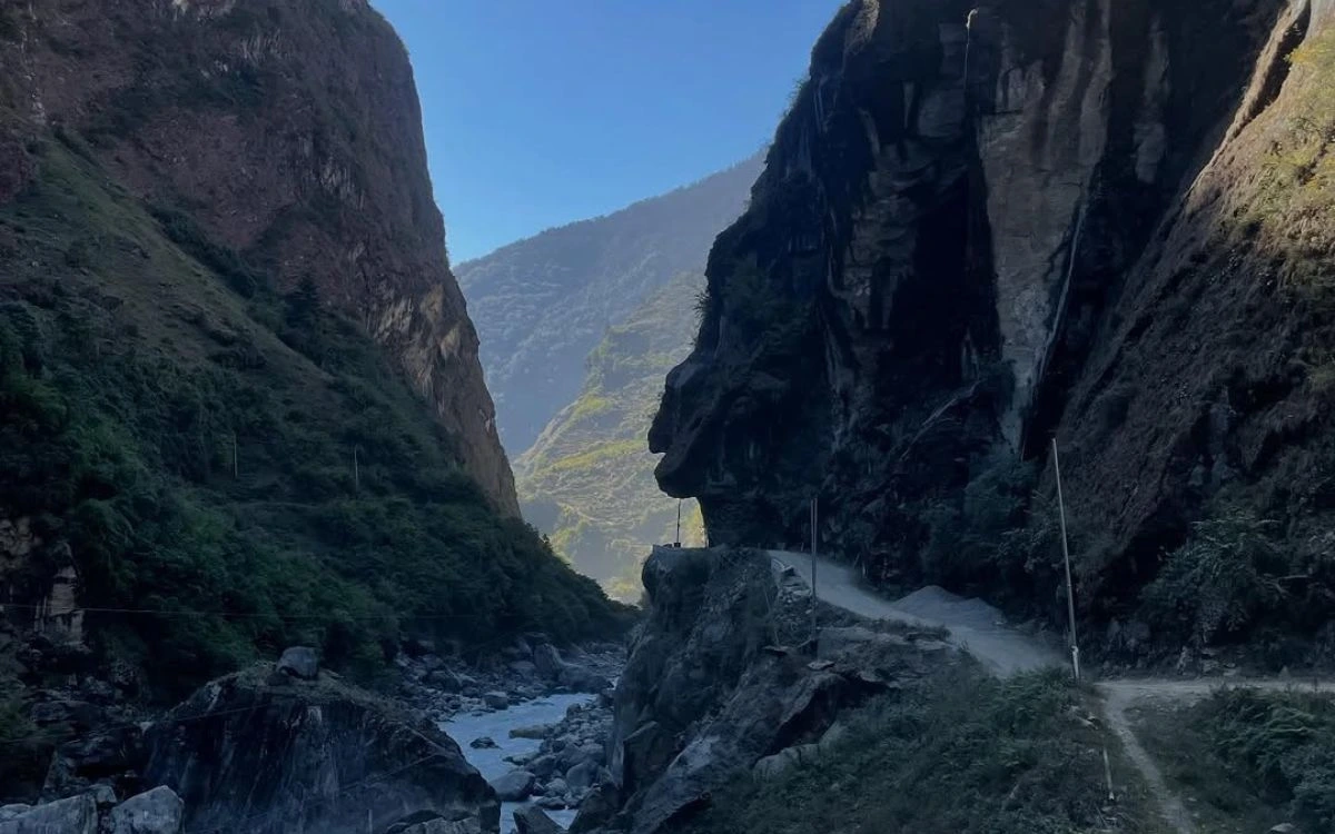 A narrow river gorge with a dirt road carved into the cliff face on the Annapurna Circuit
