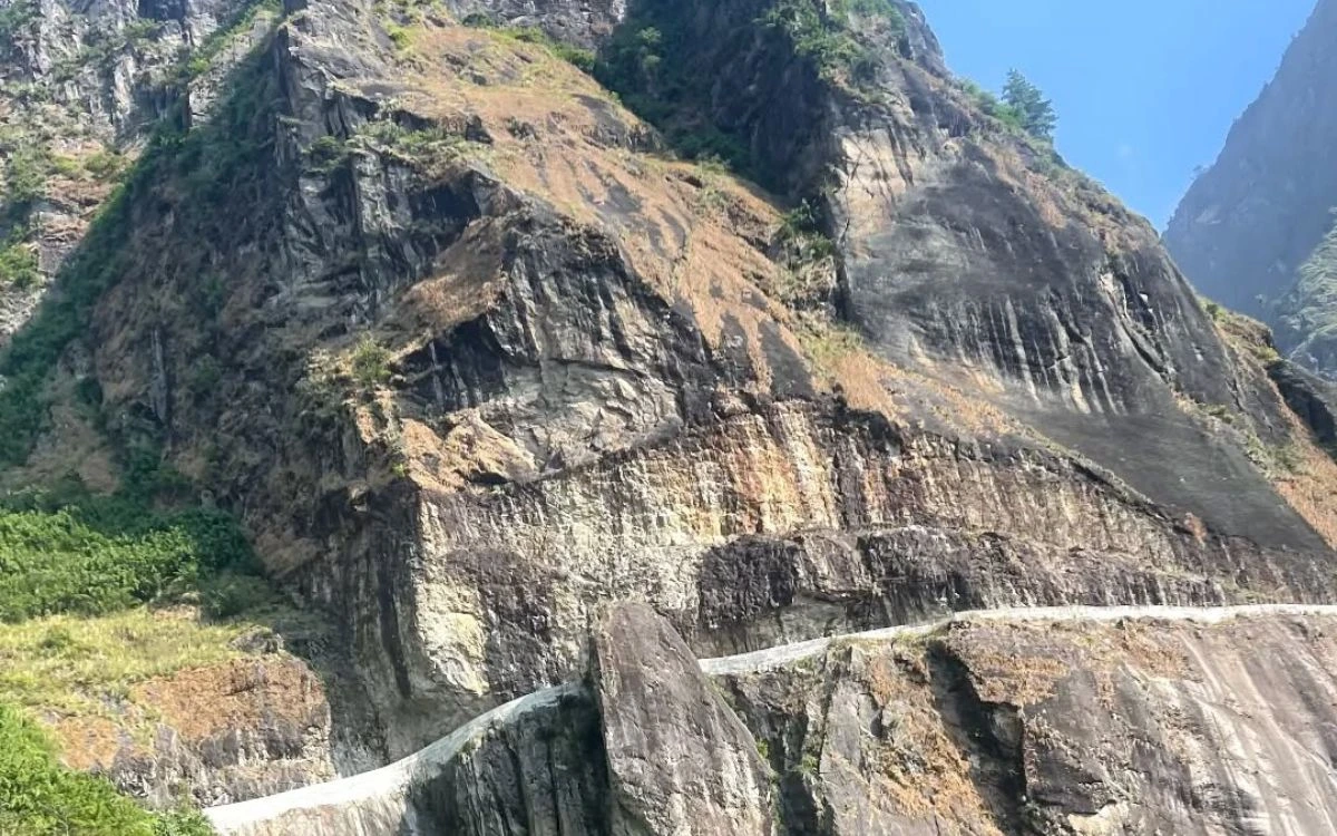 A narrow road blasted into a steep exposed rock face along the Annapurna Circuit after road construction