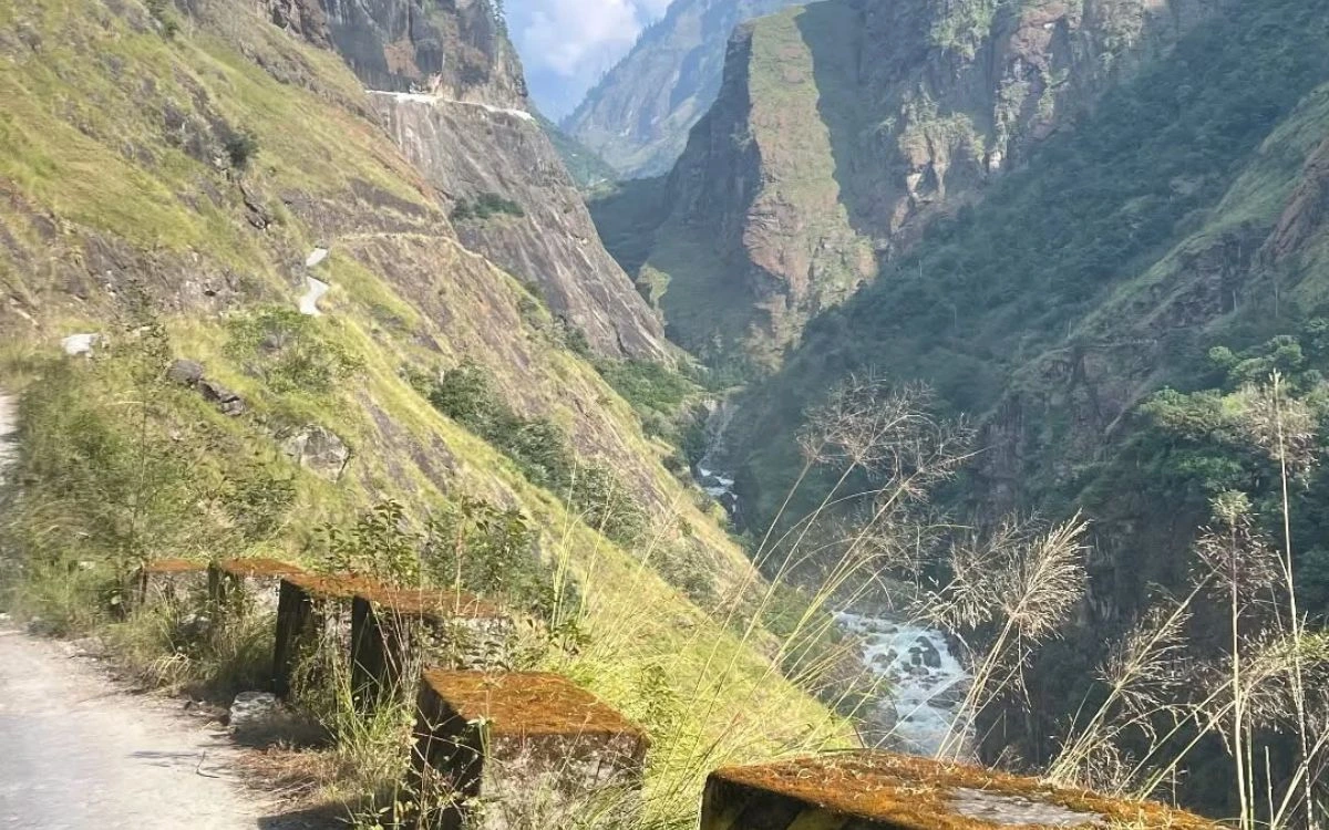 A winding mountain road overlooking a deep green river gorge on the lower Annapurna Circuit
