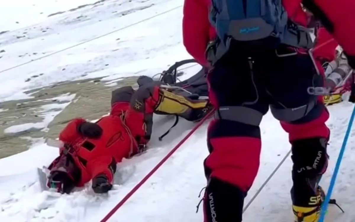 Rescue team member in red gear attending to a climber lying in snow on Mount Everest