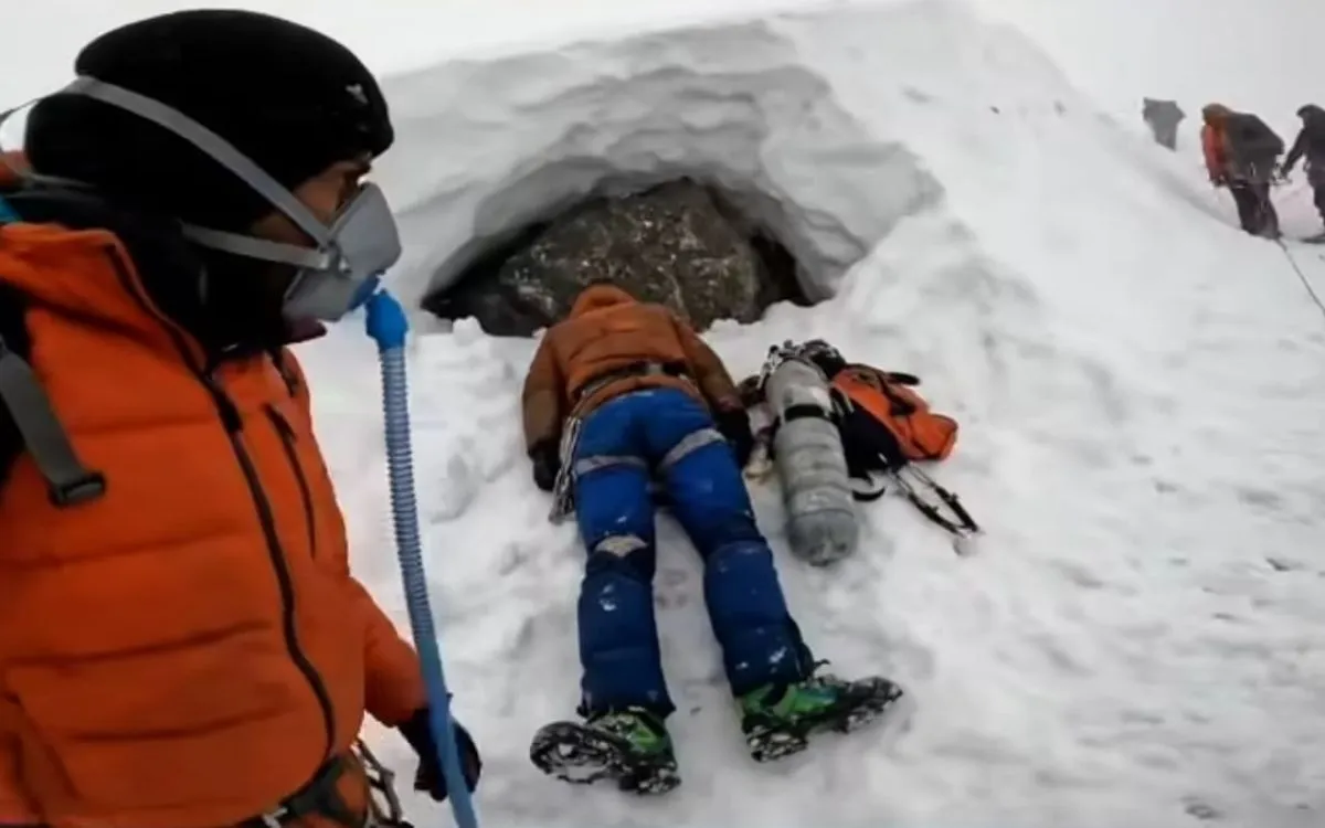 Climber attending to a dead body lying in snow near a rock shelter on Everest