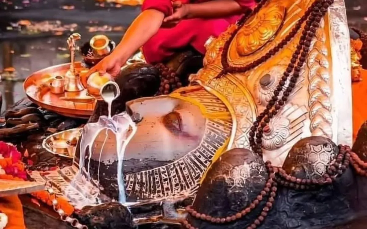 Hindu priest performing milk abhishek ritual on the Jalashayana Vishnu statue at Budhanilkantha Temple, Kathmandu