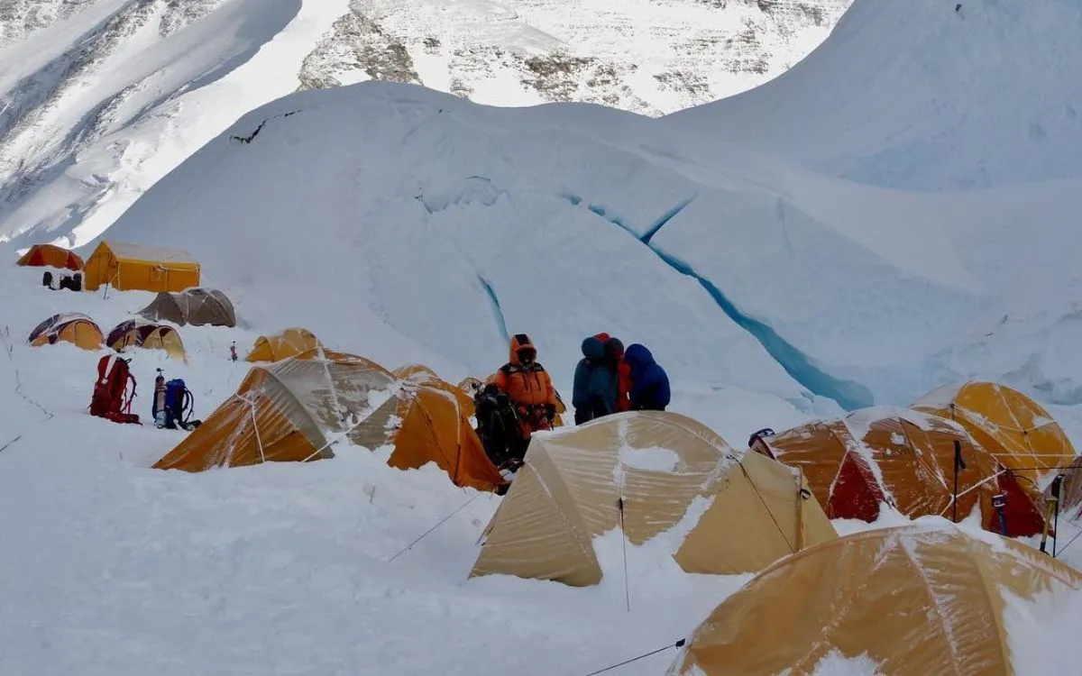 Everest high camp with yellow tents and climbers amid crevassed glacier terrain