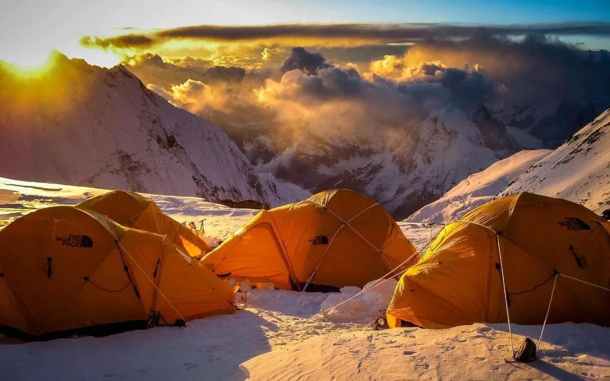 Golden hour at Everest camp with orange tents against dramatic mountain backdrop