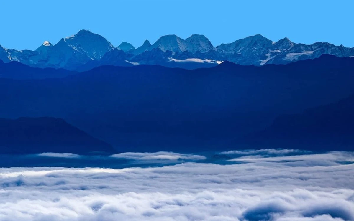 Panoramic view of the green Kathmandu valley hills with majestic snow peaks under a clear blue sky.