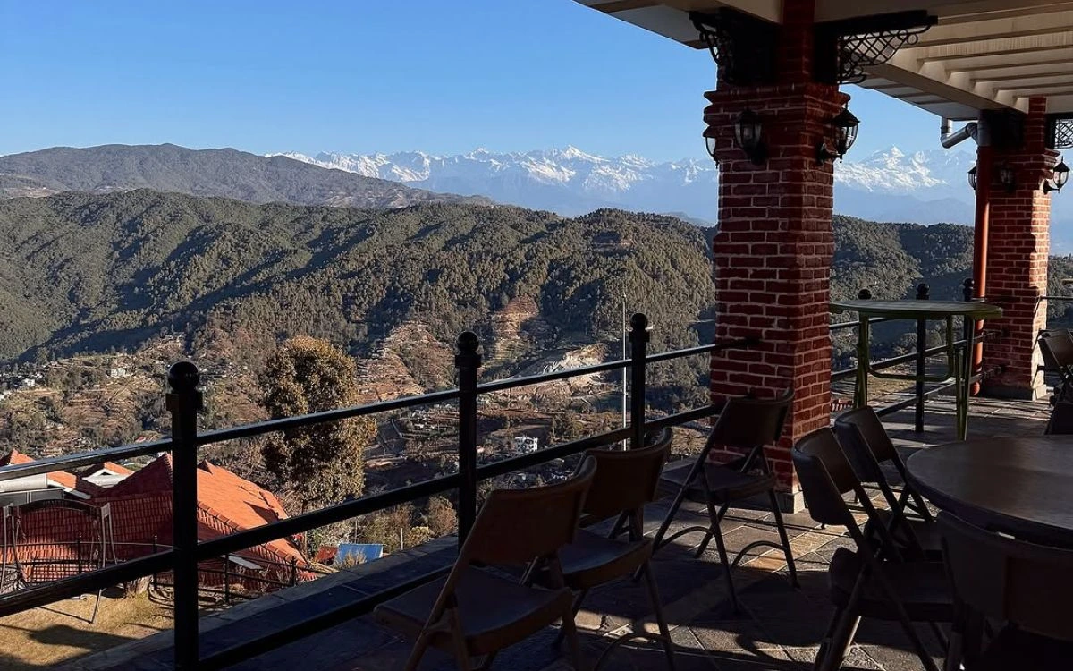 Panoramic Himalayan mountain view from a terrace in Nagarkot, Nepal, with forested hills in the foreground and snow-capped peaks visible on a clear day.