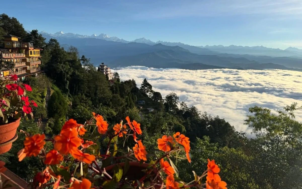 Sunrise view from Nagarkot, Nepal, featuring colorful flowers, a sea of clouds covering the valley, and the Himalayan mountain range in the background.