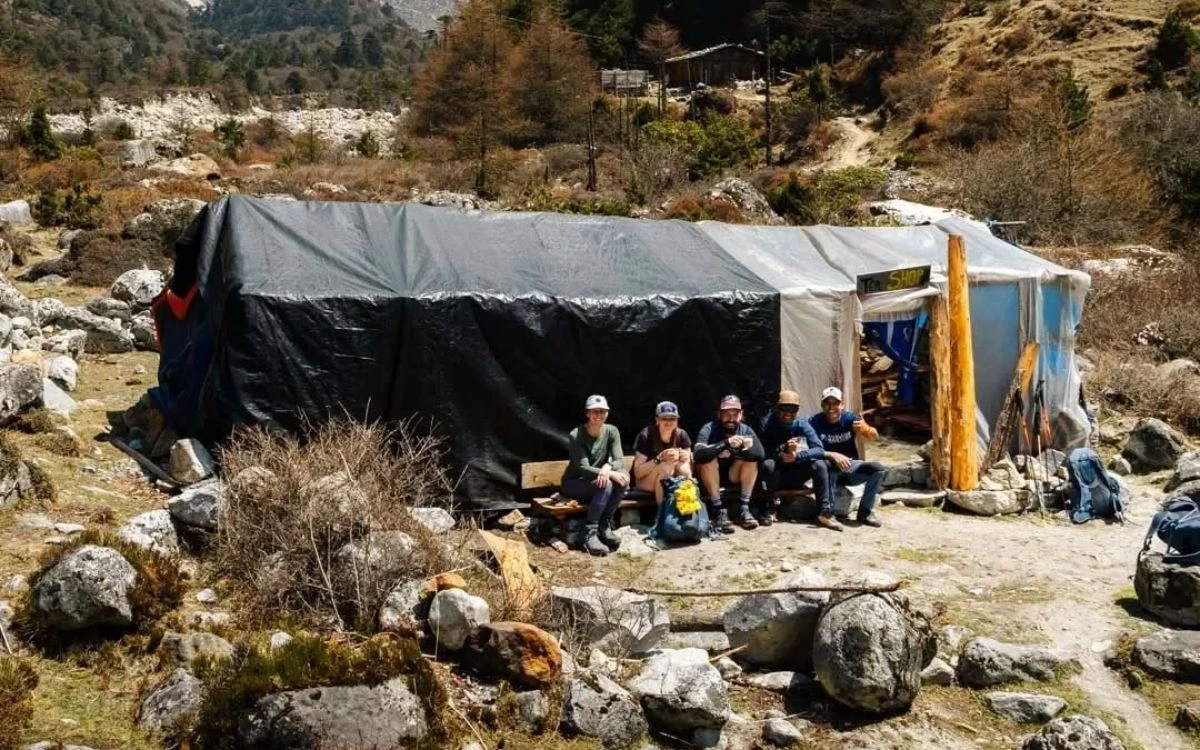Group of trekkers resting outside a makeshift tea shop shelter on the remote Kanchenjunga trail