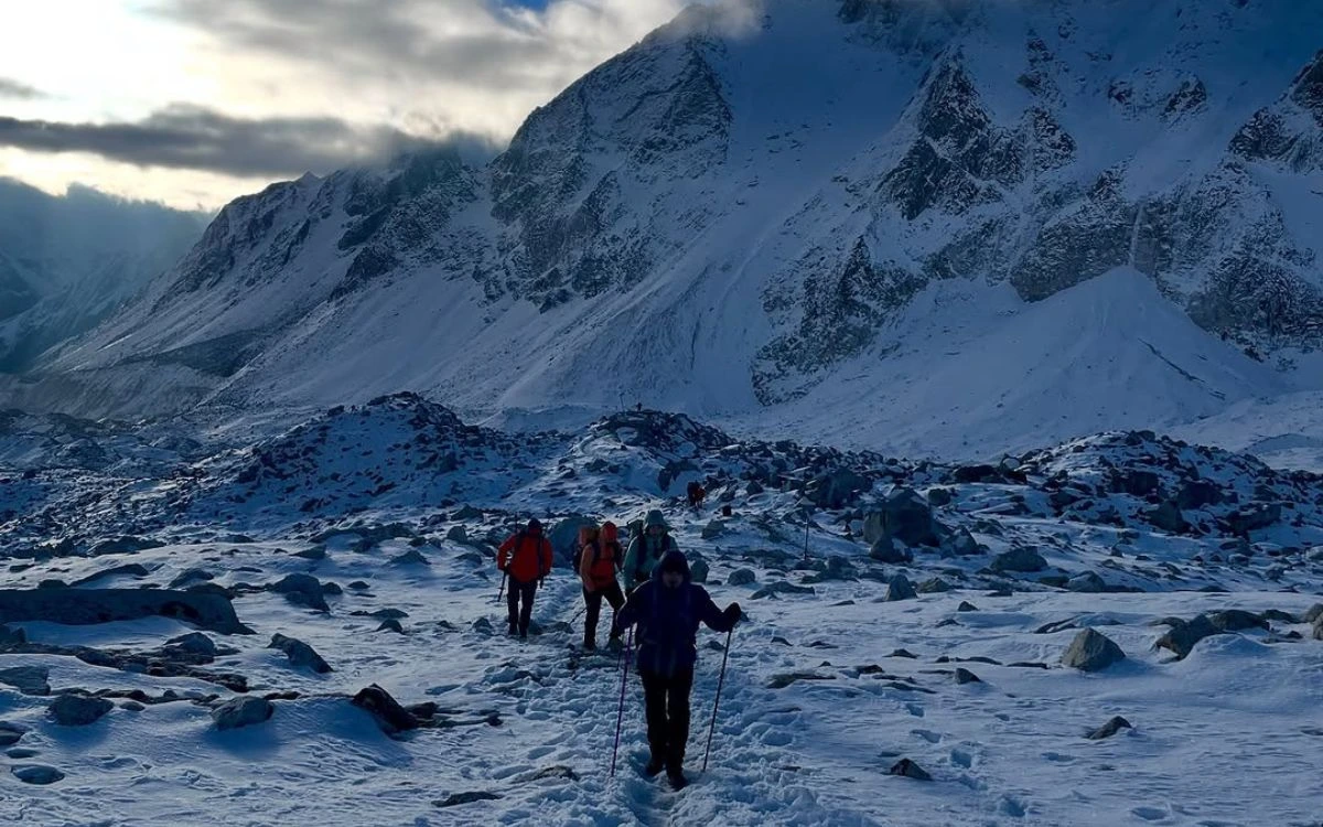Trekkers hiking through snowy terrain with dramatic Himalayan peaks in background