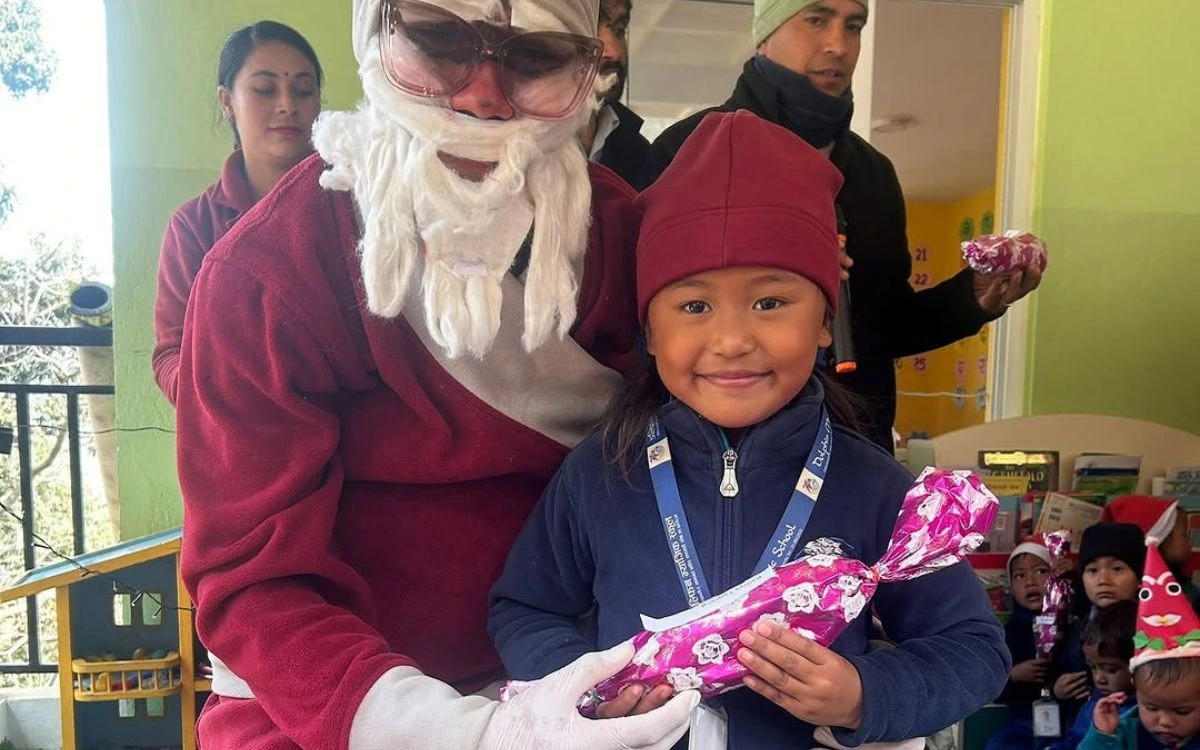 Santa Claus giving gifts to smiling Nepali child during Christmas in Nepal charity event