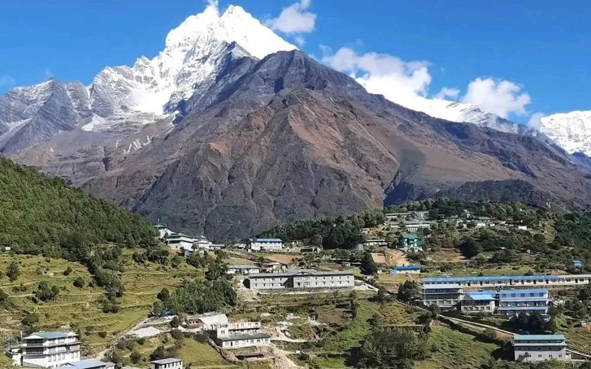Himalayan village with teahouses and lodges beneath dramatic snow-capped peak"