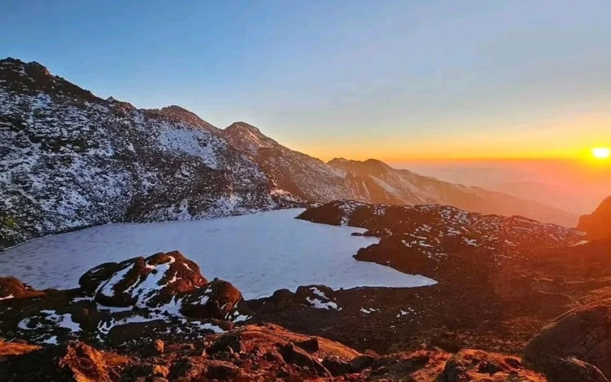 A frozen alpine lake at sunrise with snow-dusted peaks in Nepal