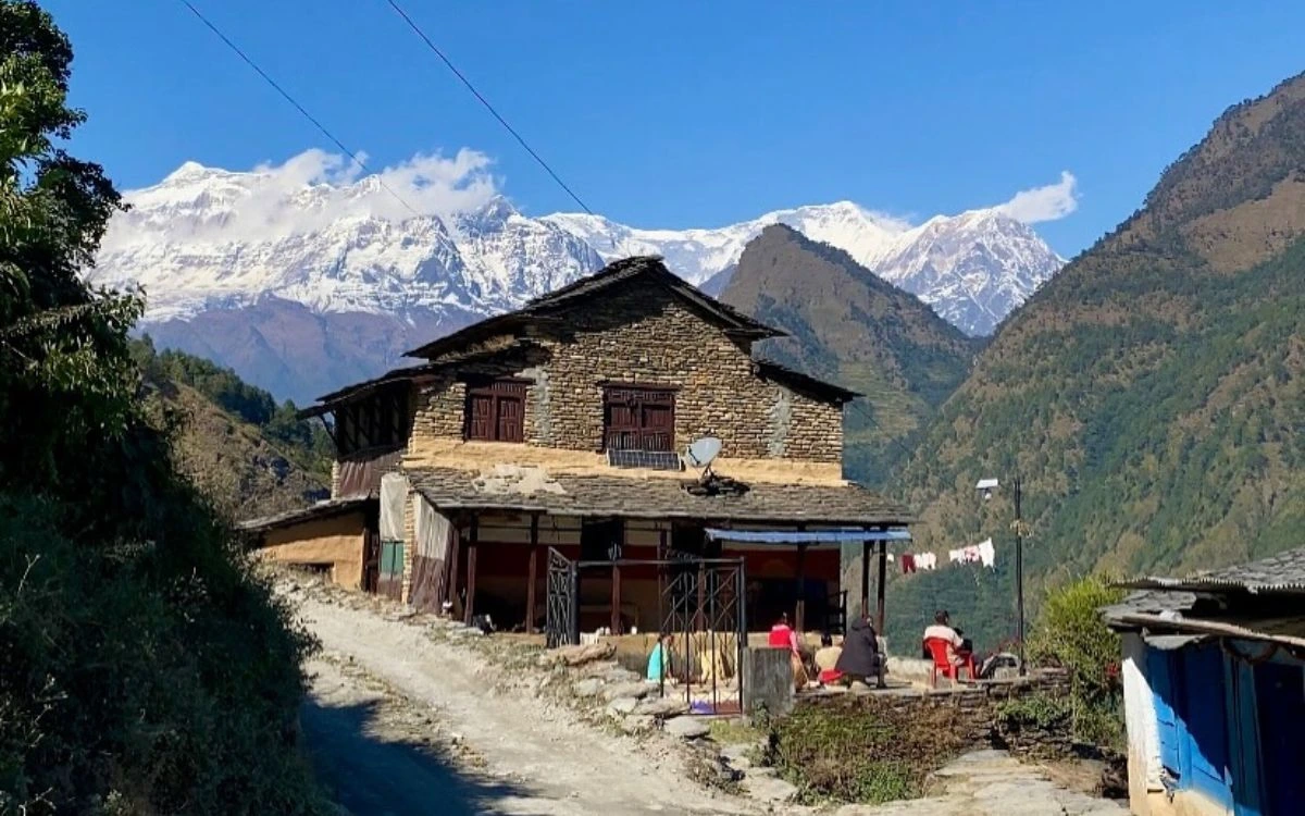 Traditional stone house in Dharapani village with snow-capped Himalayan mountains in the background