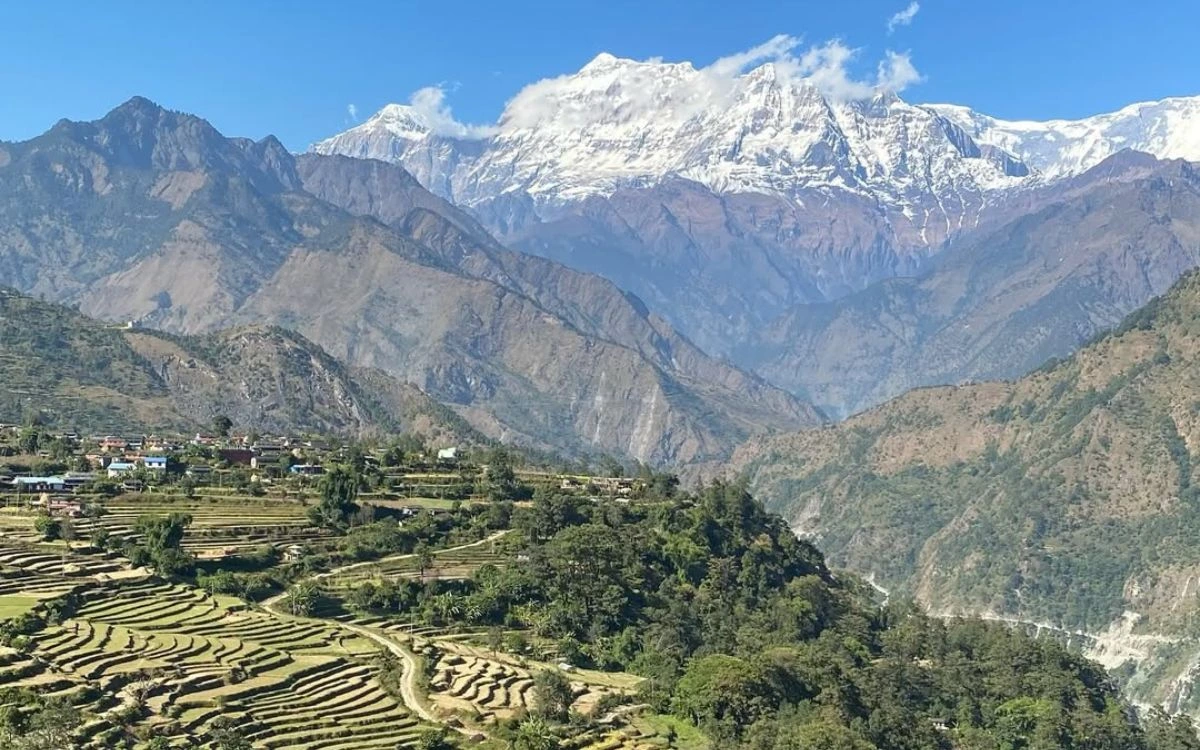 Terraced farming fields in Dharapani with village houses and snowy mountain peaks of the Himalayas