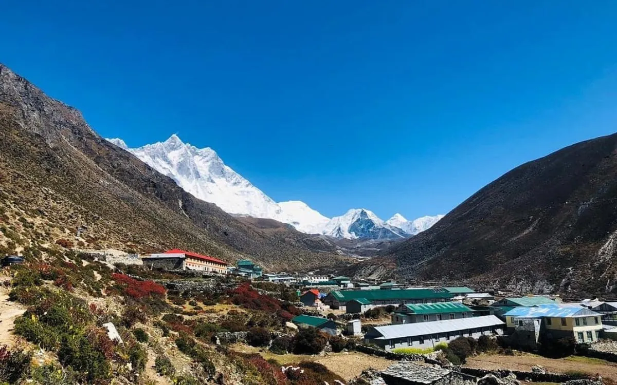 Dingboche village surrounded by hills with trekkers on trail and mountain backdrop