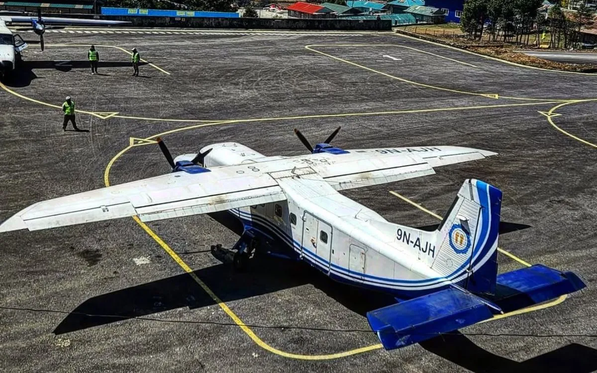 Small Twin Otter aircraft parked on tarmac at Nepal mountain airport with ground crew