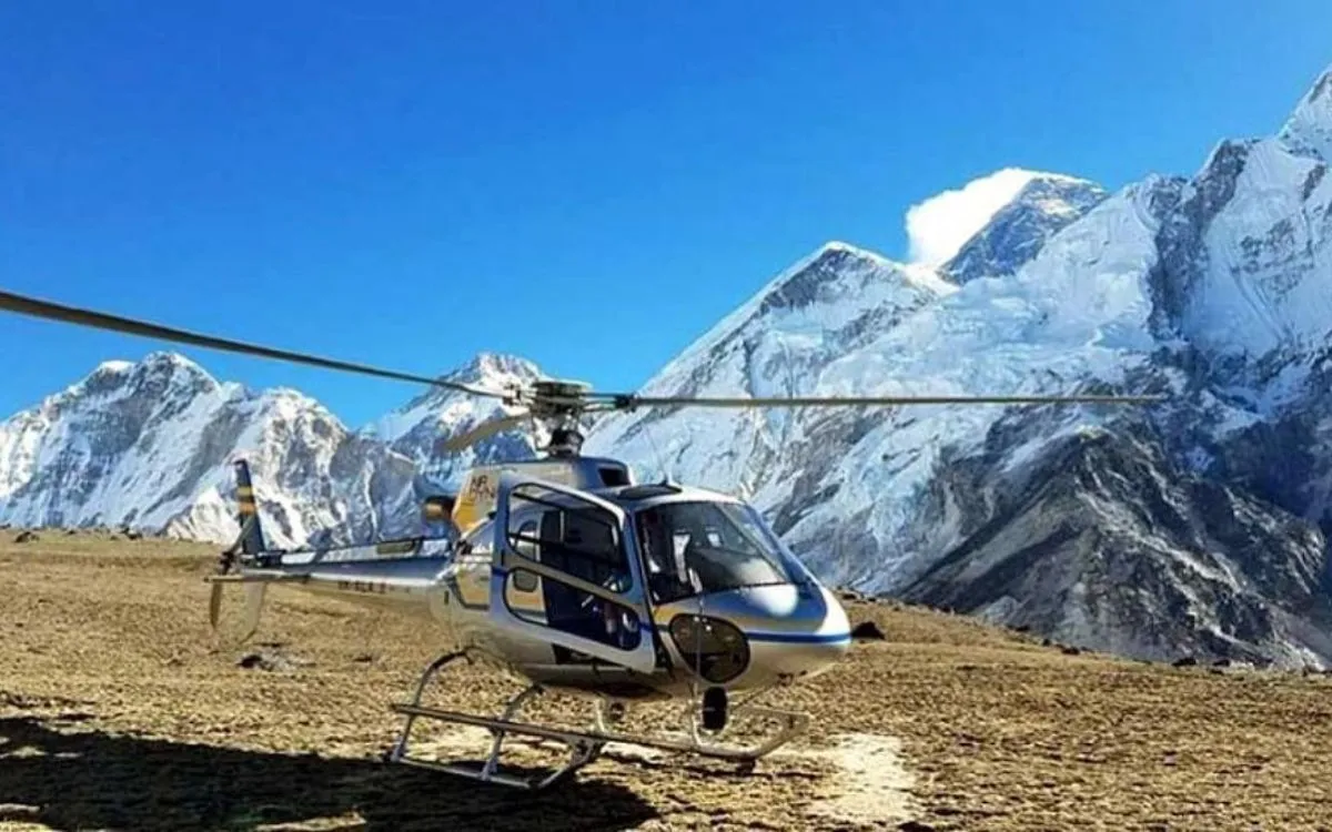 Helicopter landed on barren mountain terrain with snow-capped Himalayan peaks in the background