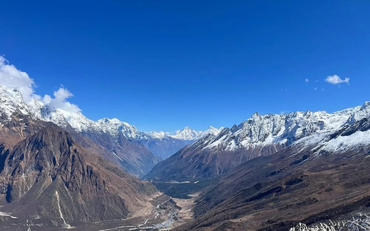 Wide valley view with Manaslu massif and snow-capped Himalayan peaks under clear blue sky