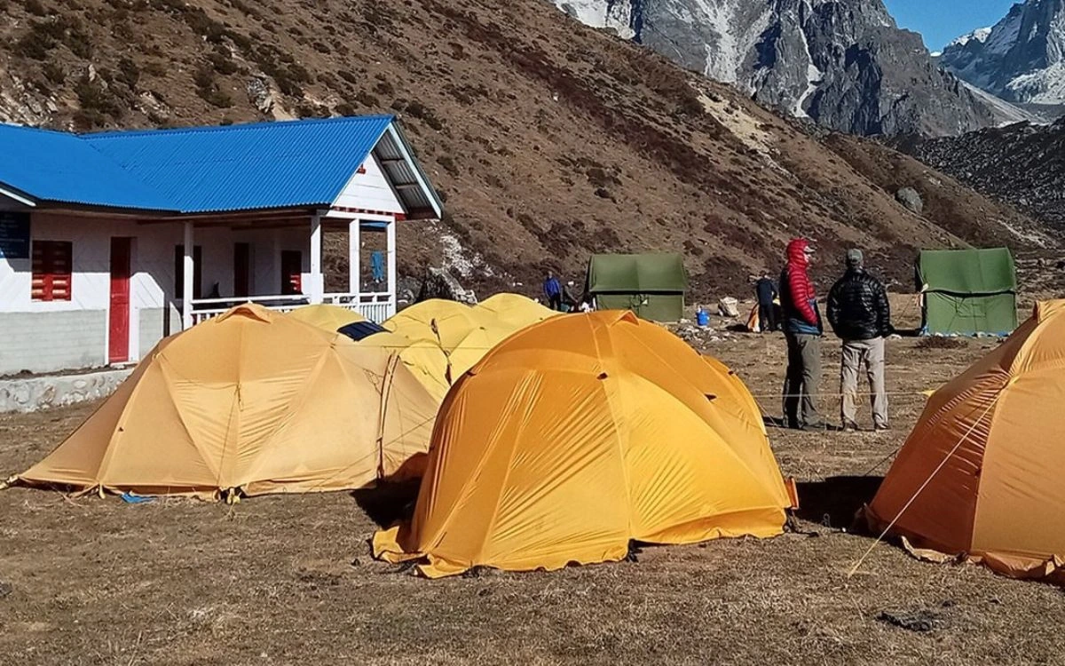 Yellow camping tents pitched near a lodge during a Kanchenjunga trek camping stop