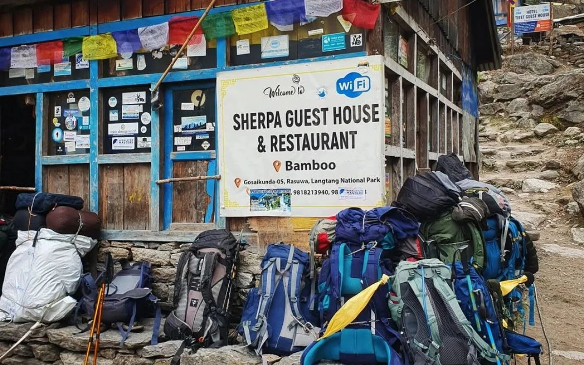 Trekking backpacks outside a Sherpa guesthouse in Nepal with prayer flags