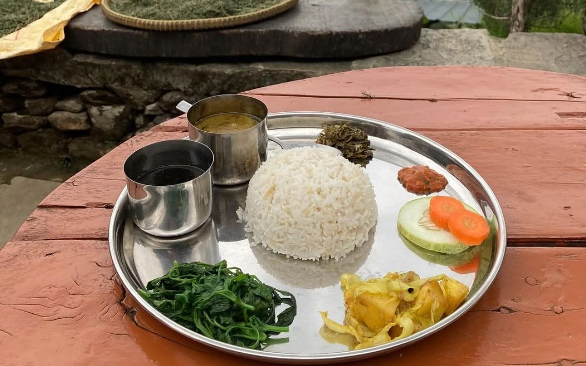 Traditional dal bhat meal with rice, lentils, vegetables, and pickle on metal plate
