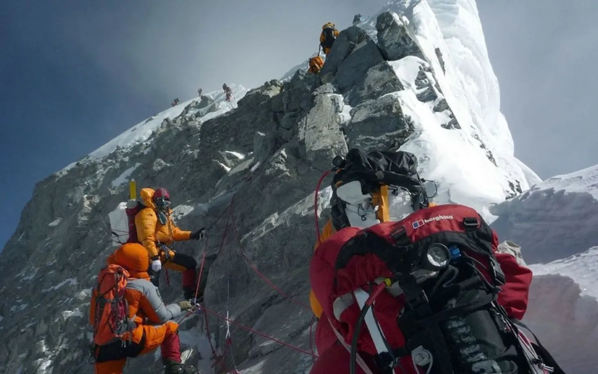Climbers ascending the Hillary Step on Mount Everest, navigating the technical rock and ice section near the summit 