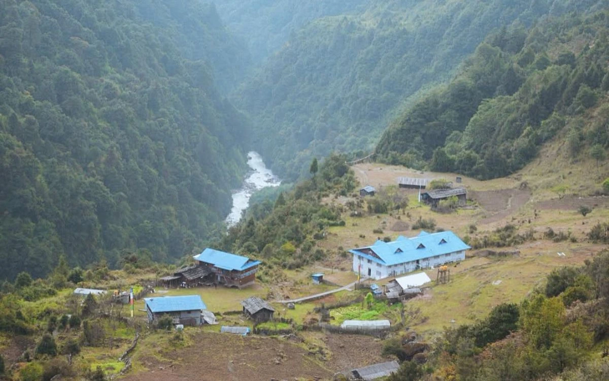 A small remote teahouse village nestled in a deep forested valley with a river below in Nepal