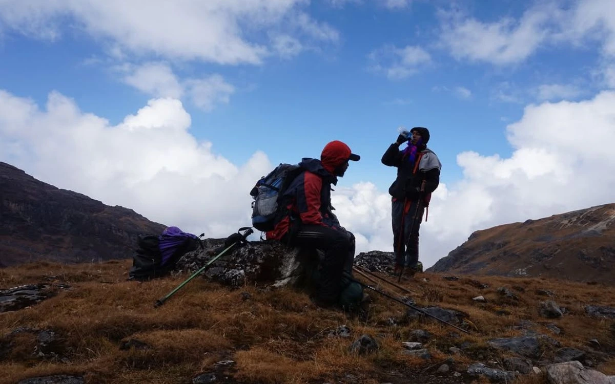 Two trekkers taking a rest break on a high alpine ridge during a group joining trek in Nepal