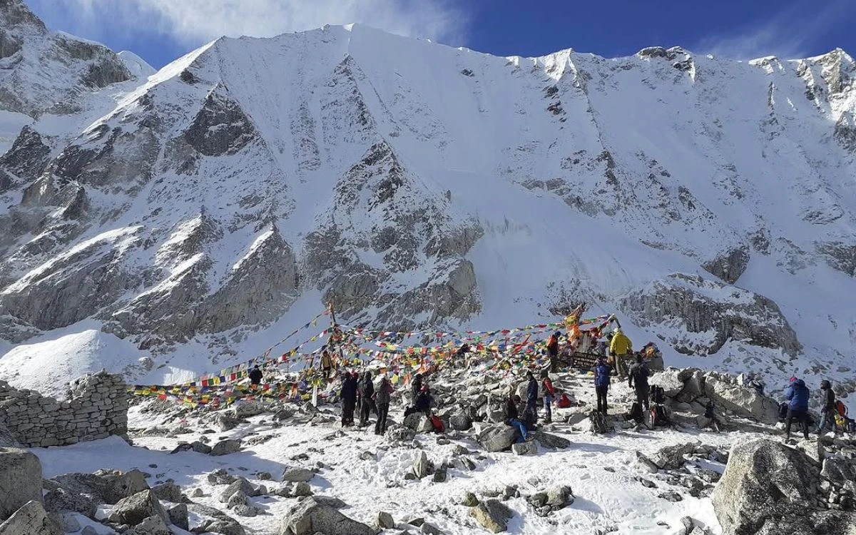 Trekkers celebrating at Larkya La Pass summit with prayer flags and snow peaks