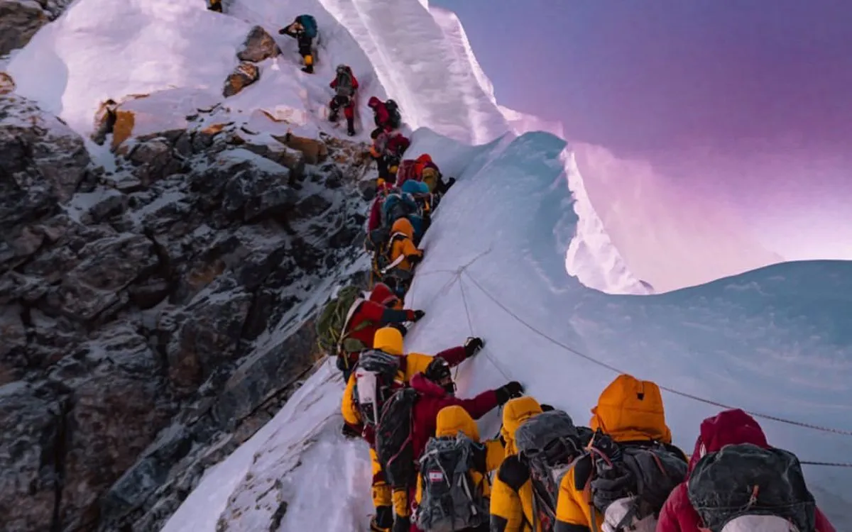 Crowd of climbers queuing at Hillary Step on Mount Everest with dramatic pink sunset sky and snow cornices