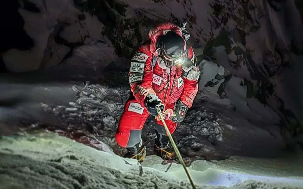 Mountaineer in red suit navigating Hillary Step at night on Mount Everest climb