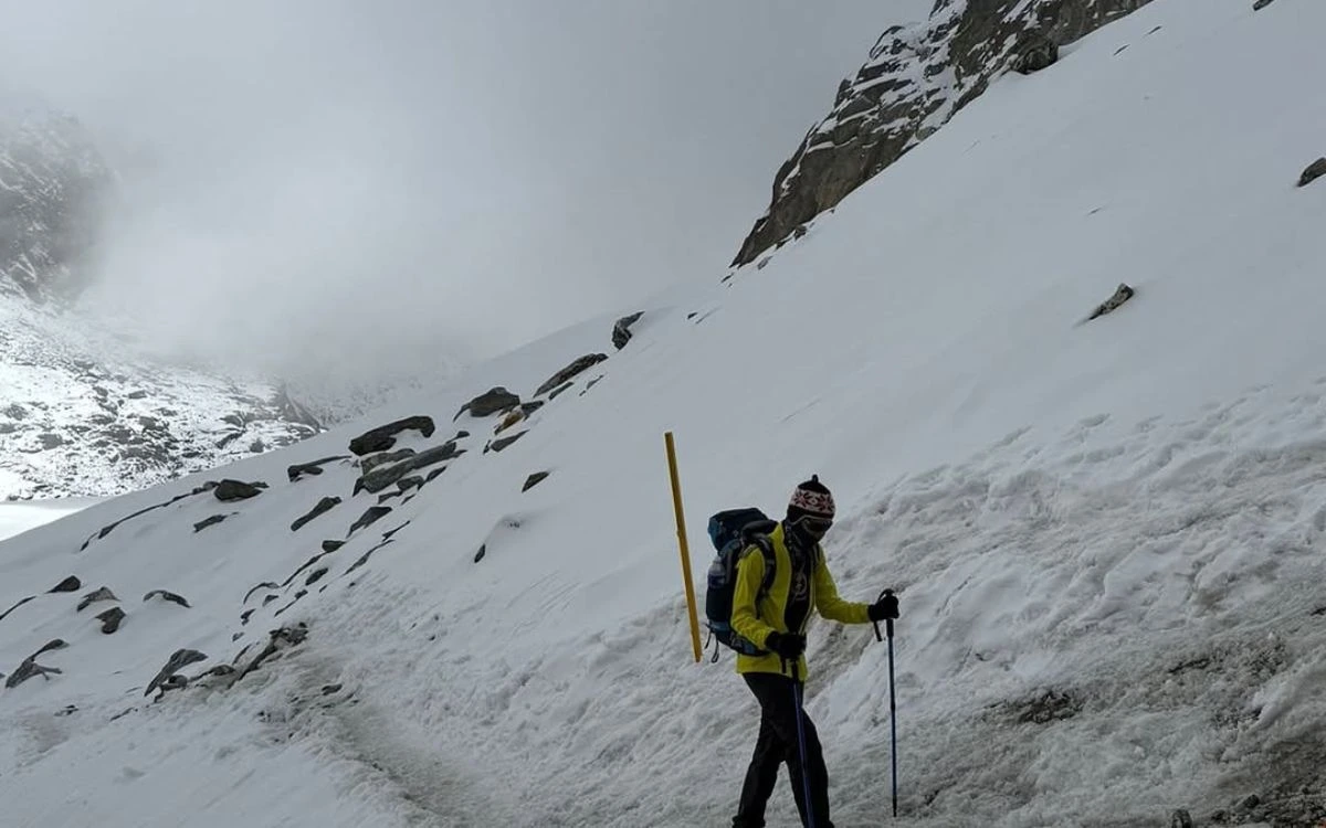 Trekking guide navigating snowy mountain pass in Nepal with hiking poles and backpack during winter trek